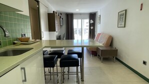 Eine Küche mit einer Arbeitsplatte, Hockern, einem Spülbecken und einem Fenster mit Vorhängen.