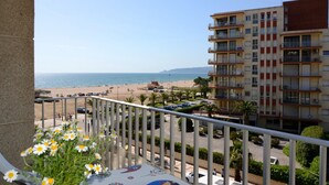 Ein Balkon mit Blick auf den Strand, ein Parkplatz und ein mehrstöckiges Gebäude mit Balkonen.