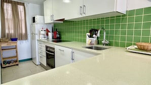 Eine Küche mit weißen Schränken, einer grünen Fliesenspiegel und einer Spüle, sowie einer Kaffeemaschine.