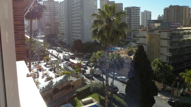 A cityscape with tall buildings, palm trees, and a busy street with cars. - EDEN PARK - 5 beds (2 BEDROOMS) (Benidorm)
