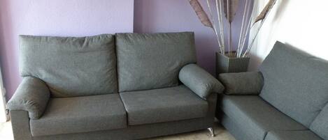 A living room with a grey sofa, a black coffee table, and decorative items including tall grasses and a small basket.