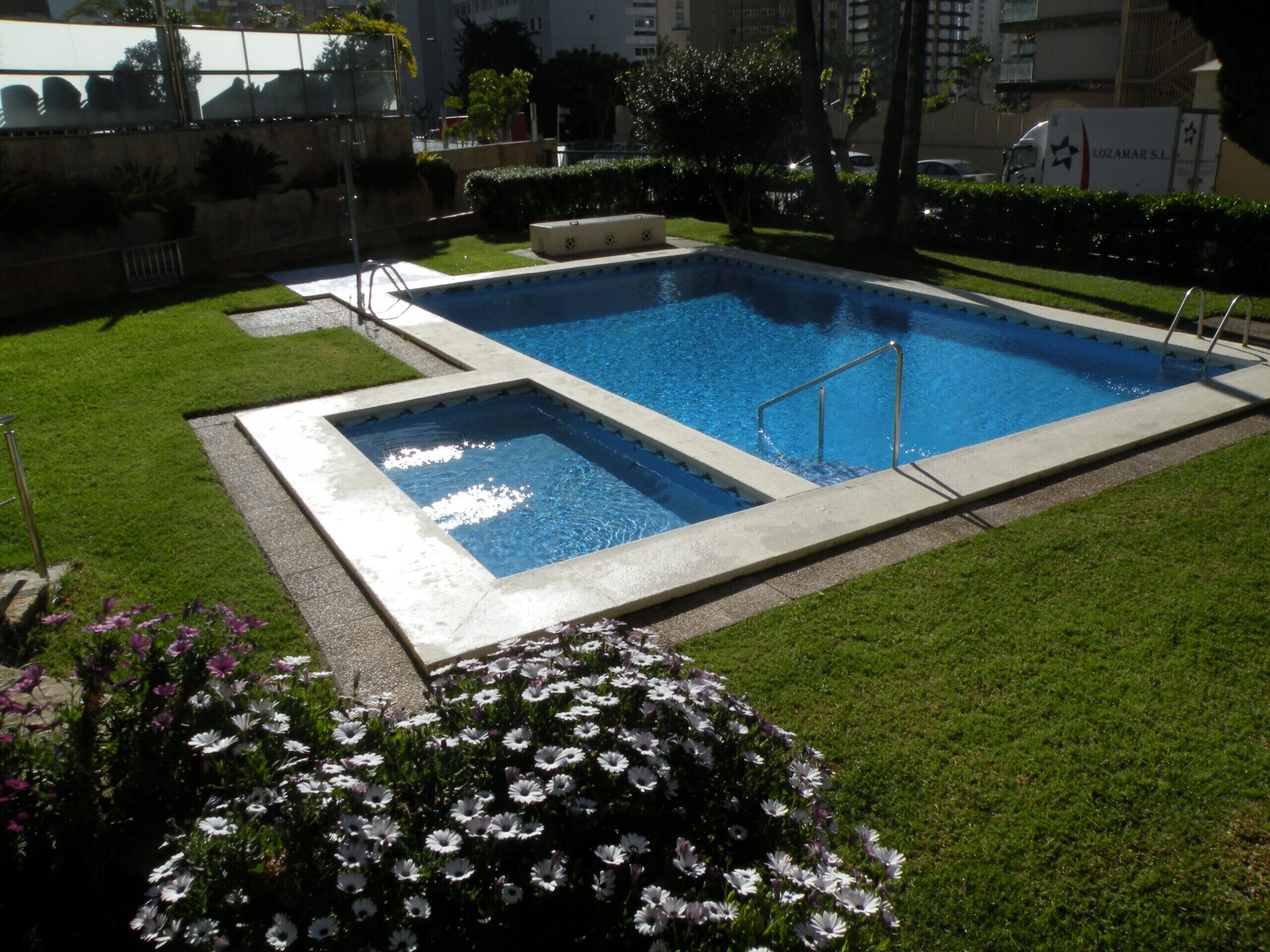 Une piscine rectangulaire avec un escalier en métal et une piscine plus petite adjacente.