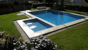 Une piscine rectangulaire avec un escalier en métal et une piscine plus petite adjacente.
