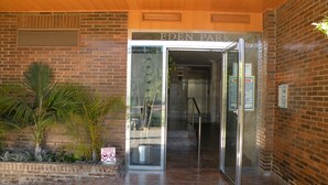 The entrance to Eden Park with a glass door, a brick wall, and a palm plant. - EDEN PARK - 5 beds (2 BEDROOMS) (Benidorm)