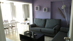 A living room with a grey sofa, a black coffee table, and a dining area with white chairs and a table. - EDEN PARK - 5 beds (2 BEDROOMS) (Benidorm)