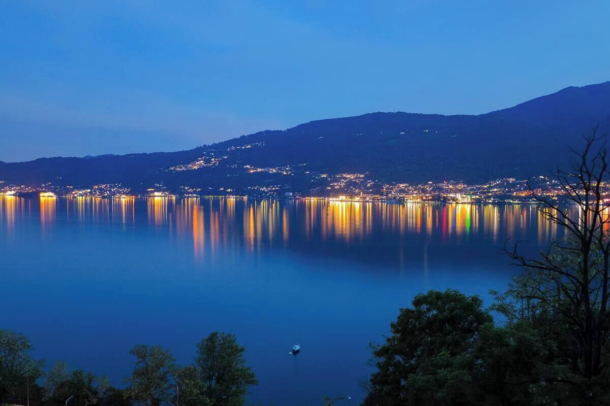Un lac paisible au crépuscule, où les lumières de la ville se reflètent sur l’eau.