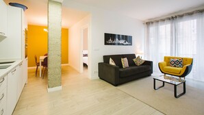 Een moderne woonkamer met een bank, een gele fauteuil en een eethoek met een tafel en stoelen.