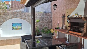 An outdoor patio with wicker furniture, a barbecue grill, and a tiled backsplash.