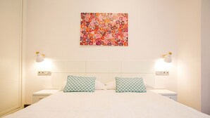 A hotel room with a large bed, two bedside tables, two lamps, and a colorful abstract painting on the wall. - 4 Bella Easo B San Marcial 28 (San Sebastián)