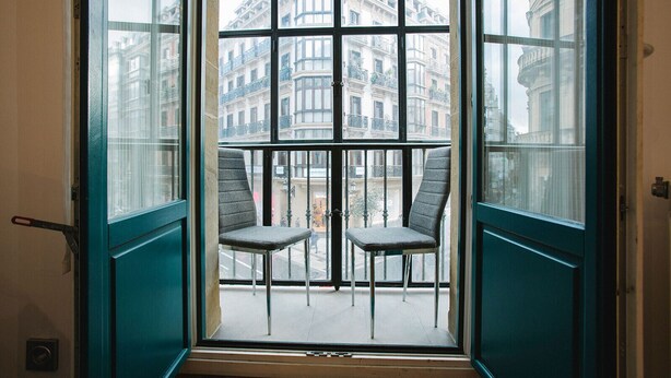 A room with a large window, two chairs, and a view of buildings. - 4 Bella Easo B San Marcial 28 (San Sebastián)
