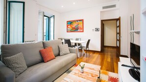 A modern living room with a grey sofa, a dining table, and a colorful abstract painting. - 4 Bella Easo B San Marcial 28 (San Sebastián)