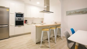 Una cocina moderna con una isla central, electrodomésticos de acero inoxidable y una zona de comedor con taburetes de bar.