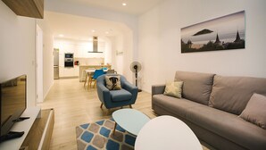 Una sala moderna con sofá, sillón y un comedor al fondo.