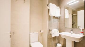 Een moderne badkamer met toilet, wastafel en douche.