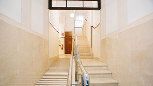 Un escalier muni d’une rampe, d’un extincteur et d’une porte en haut.