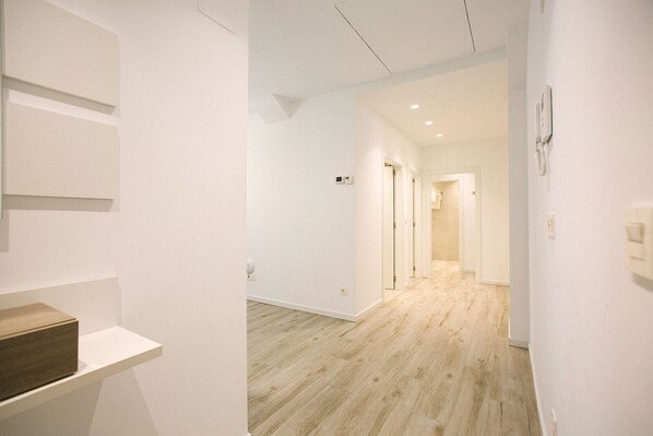 A hallway with wooden flooring, white walls, and a door leading to another room. - Gloria Suites 3 - 2 dormitorios (San Sebastián)