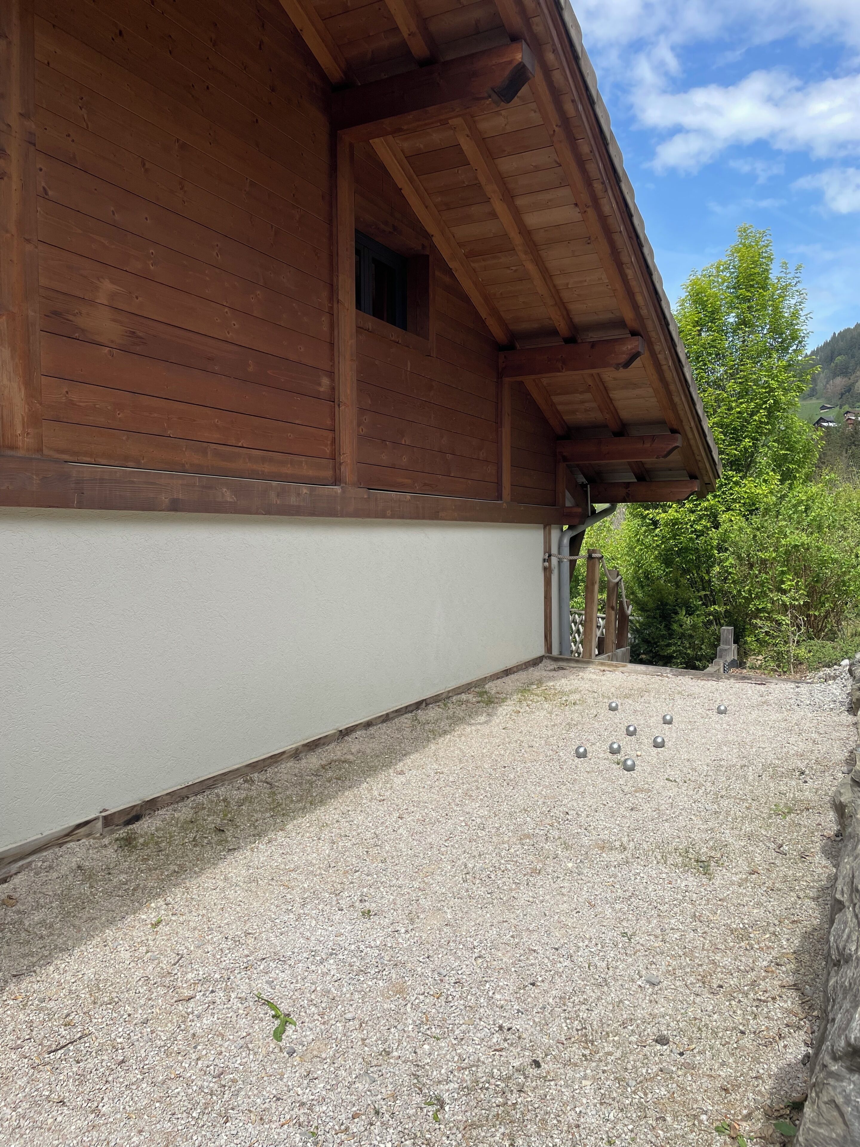 A wooden building with a gravel driveway and a clear sky.