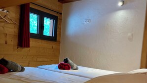 A room with a wooden ceiling, a window with a red curtain, and a bed with white bedding. - 14-Guest Chalet with Hot Tub, Sauna & Private Cinema – 3 Minutes from Châtel (La Chapelle-D'abondance)