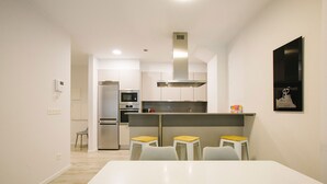 A modern kitchen with a central island, stainless steel appliances, and a dining area with white chairs. - M Gloria Suites 5 1C  inner courtyard, one bedroom (San Sebastián)