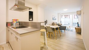 A modern kitchen with a central island, dining area with chairs, and a view to a balcony. - M Gloria Suites 5 1C  inner courtyard, one bedroom (San Sebastián)