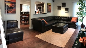 A modern living room with a sectional sofa, a dining area, and a kitchen in the background.