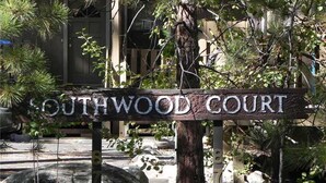 A wooden sign with the text "SOUTHWOOD COURT" in a rustic style, surrounded by greenery and rocks.