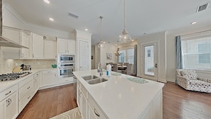 A modern kitchen with white cabinetry, stainless steel appliances, and a large island with a sink. - "Mint Julep" at Prominence - 3 BR/ 2.5 BA - Sleeps 9 - Six Passenger LSV Included! (Watersound)