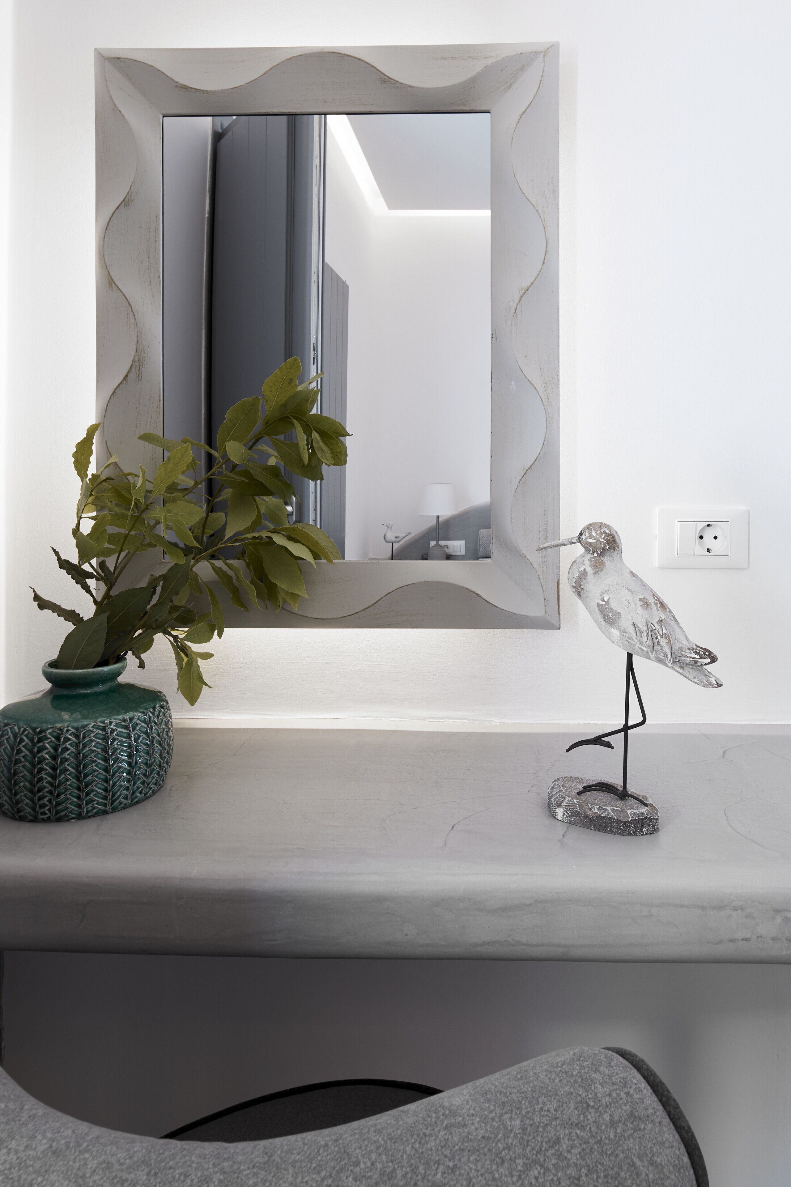 A bathroom vanity with a mirror, a potted plant, and a bird sculpture.