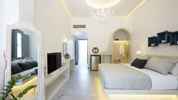 Una habitación de hotel moderna con una cama grande, televisión, espejo y candelabro.