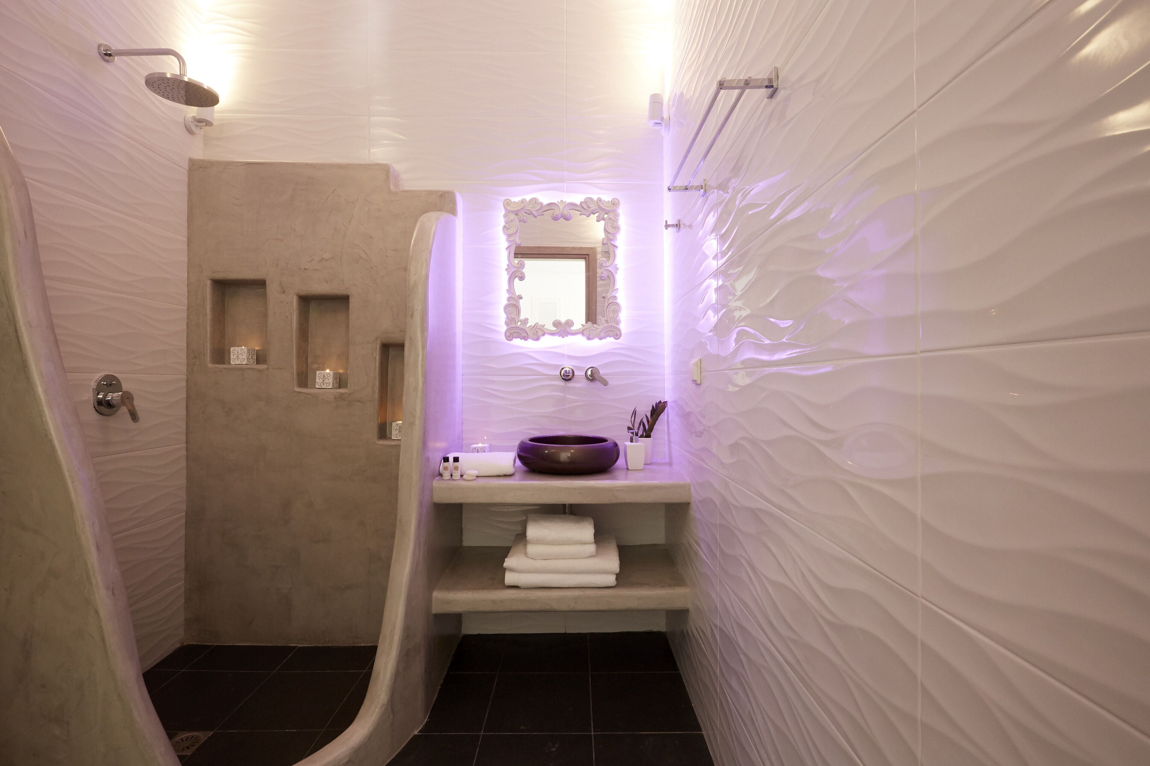 Baño de diseño moderno con ducha integrada, tocador con lavabo y espejo sobre el lavabo.