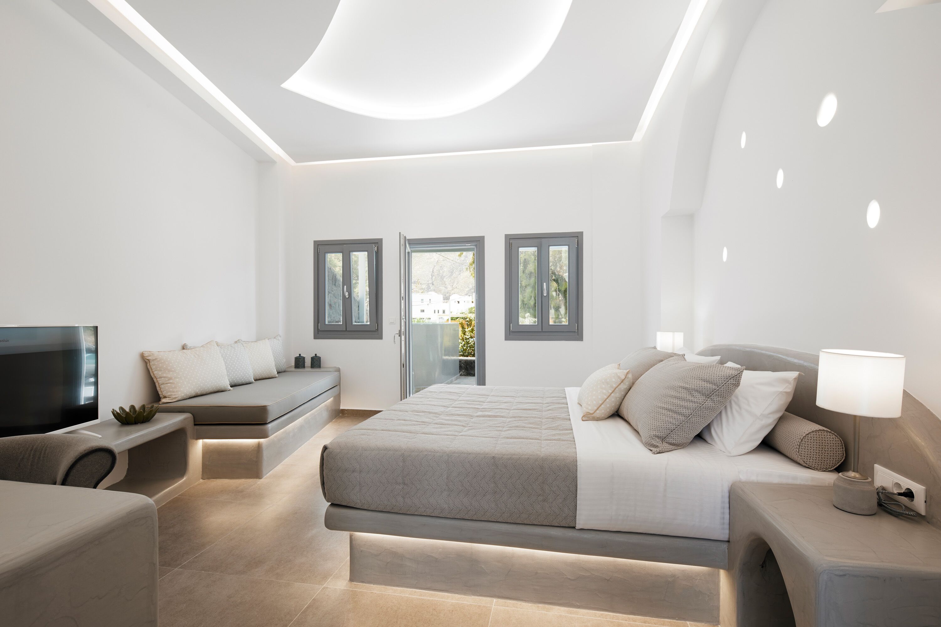 A modern bedroom with a bed, bedside table, and a TV.