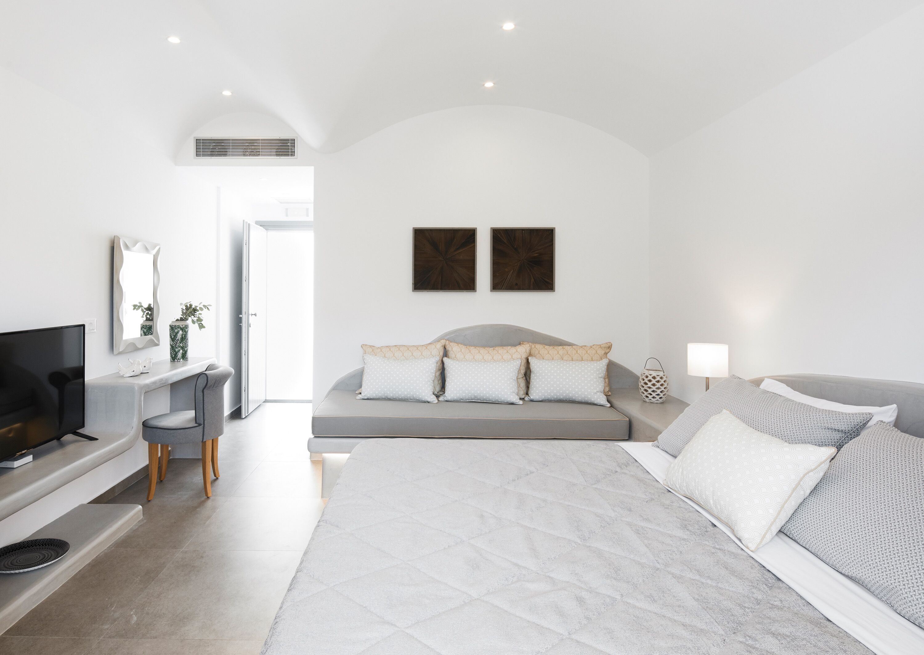 A modern bedroom with a bed, a TV, a desk, and a chair.