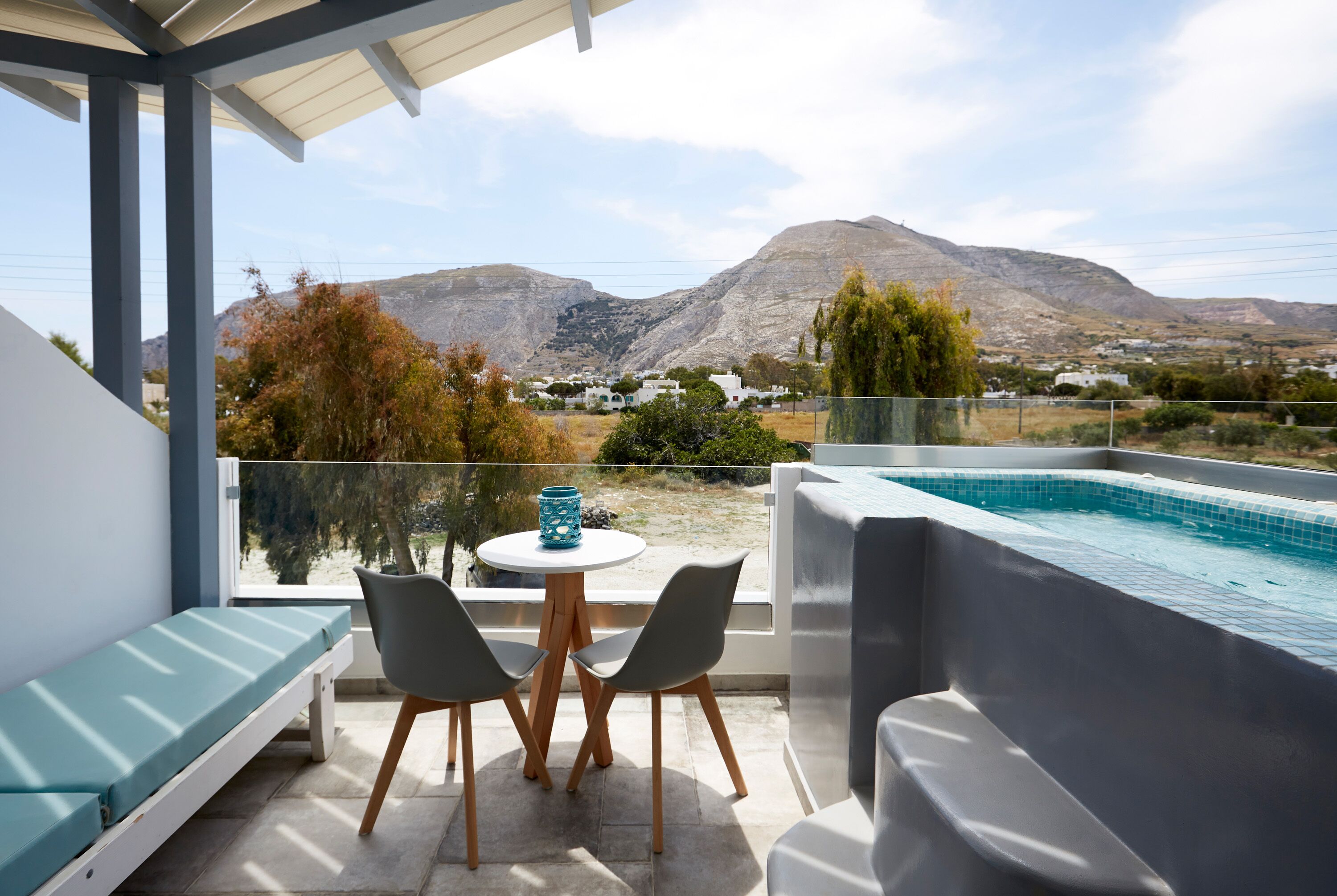 Un balcón con piscina, zona de estar y vistas a las montañas.