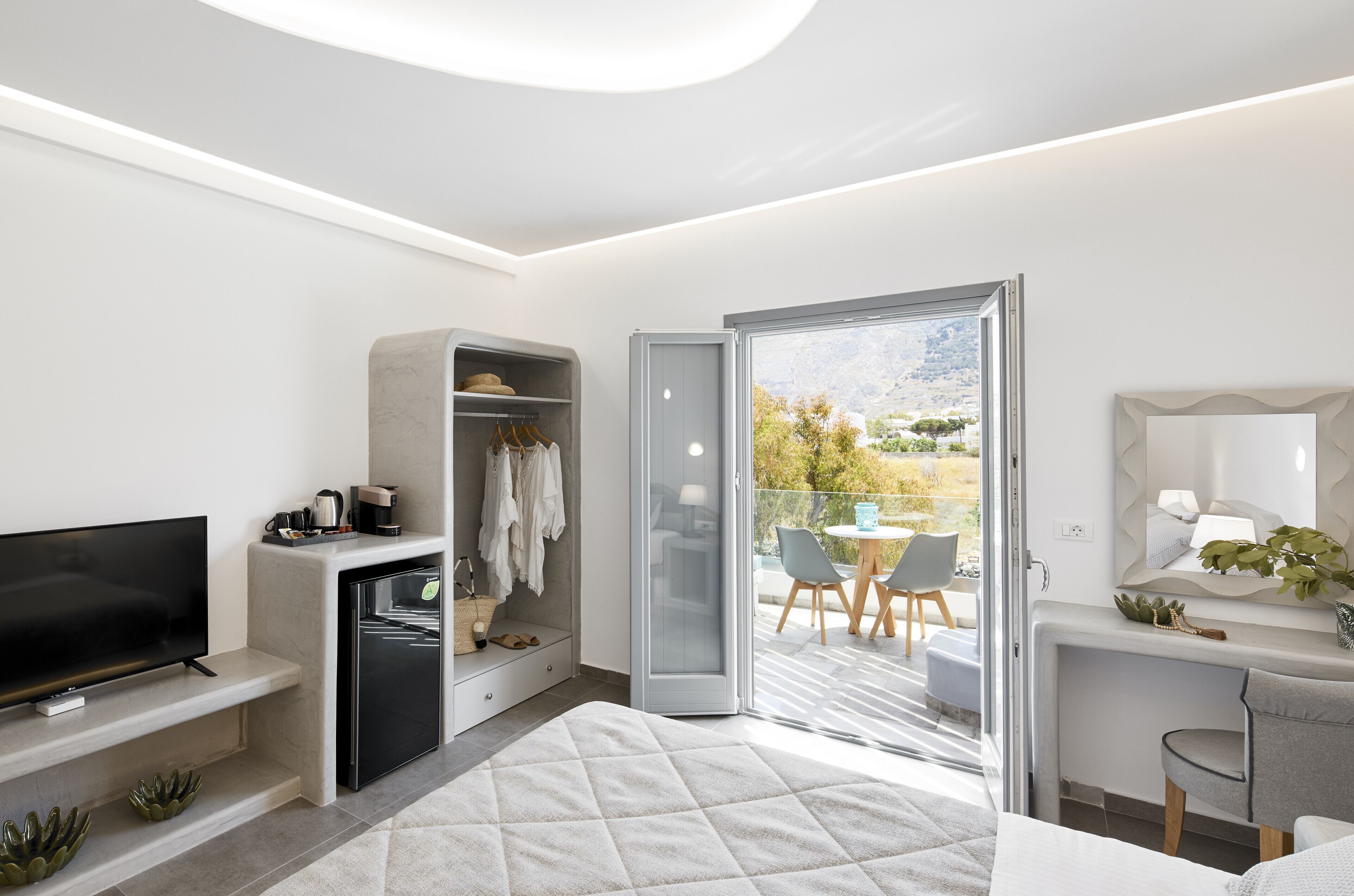 Une chambre moderne équipée d’une télévision, d’une armoire et d’un balcon avec une table et des chaises.