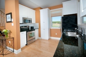 Enjoy cooking in this well-equipped kitchen with a refrigerator, microwave, and oven, and take in the view from the window.