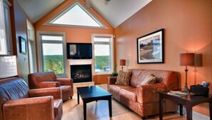 Una sala de estar con chimenea, sofás de cuero, una mesa de centro y un televisor.