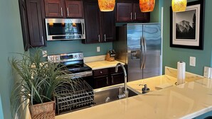 A modern kitchen with dark wooden cabinets, stainless steel appliances, and a marble countertop.
