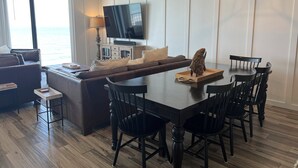 Una sala de estar moderna con un televisor grande, una mesa de comedor de madera y un sofá.