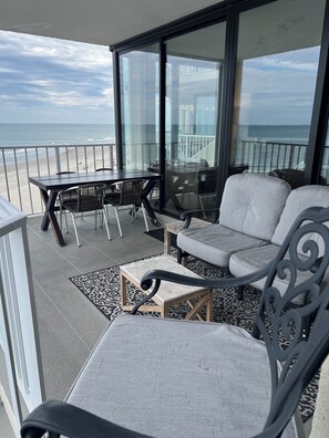 Un balcon avec une table et des chaises, un canapé et un tapis à motifs.