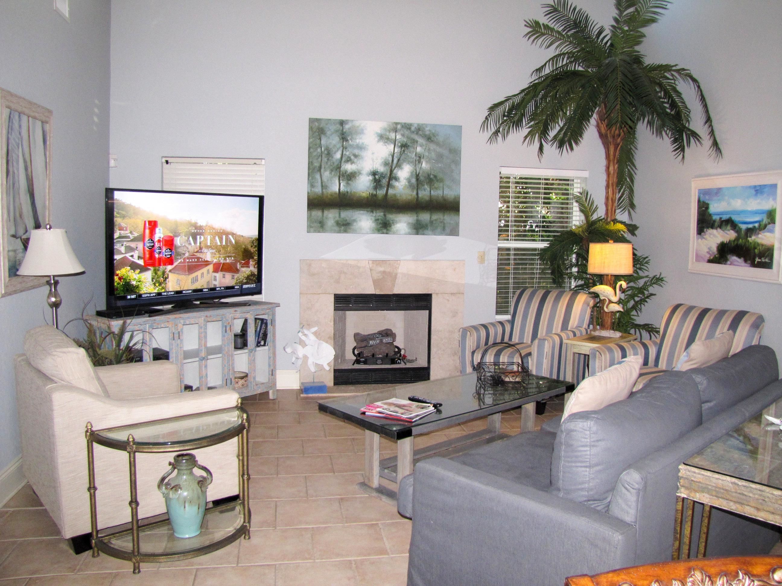 A living room with a television, sofa, armchair, coffee table, and a fireplace.