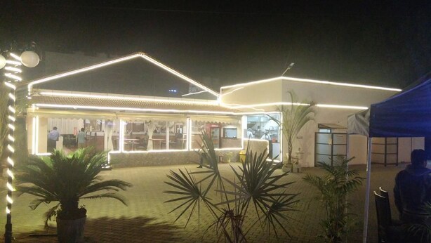 A building with a flat roof and a large entrance area. There are potted plants in the foreground. - Hotel RR Grand (Bengaluru)