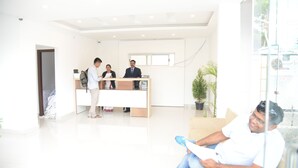 A modern reception area with a reception desk, a waiting area, and a glass partition. - Hotel RR Grand (Bengaluru)