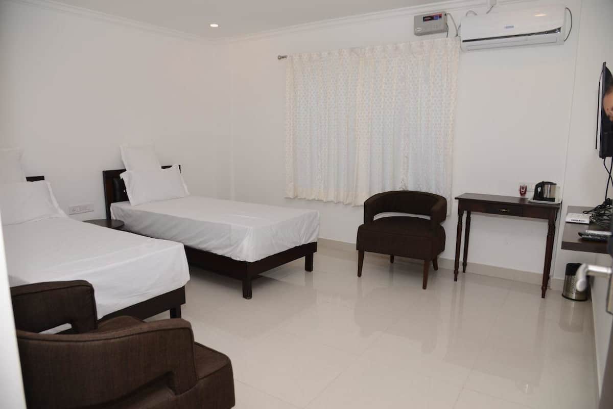 A hotel room with two beds, a desk, a chair, and an air conditioning unit.