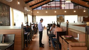 A spacious restaurant with high ceilings, wooden beams, and large windows. - Hotel RR Grand (Bengaluru)