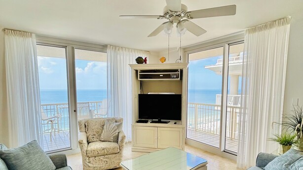 A living room with a sofa set, a television, and a ceiling fan.