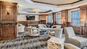 A spacious living room with a fireplace, wooden paneling, and a large television.