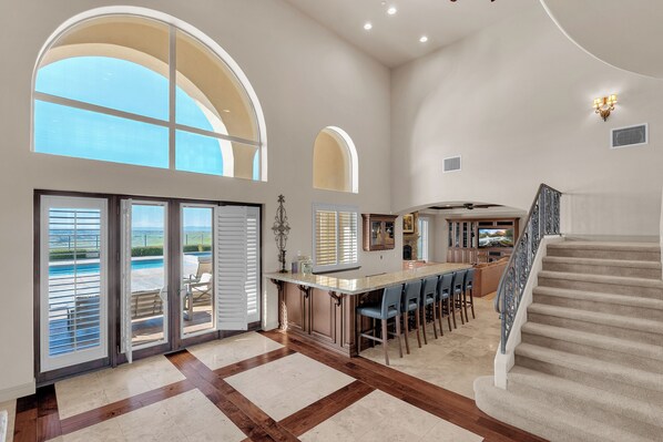 A spacious interior with a large kitchen island, a dining area, and a staircase leading to an upper level. - Pool + Spa + Panoramic Views | Paso Wine Country | The Shandon House (Shandon)