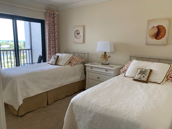 Une chambre d’hôtel avec deux lits, une table de chevet, une lampe et une vue sur l’extérieur.