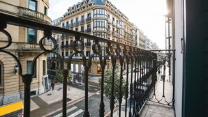 A balcony with wrought iron railings overlooking a street with buildings.