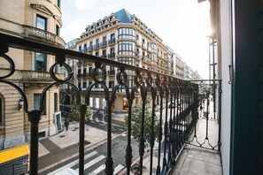 A balcony with wrought iron railings overlooking a street with buildings.